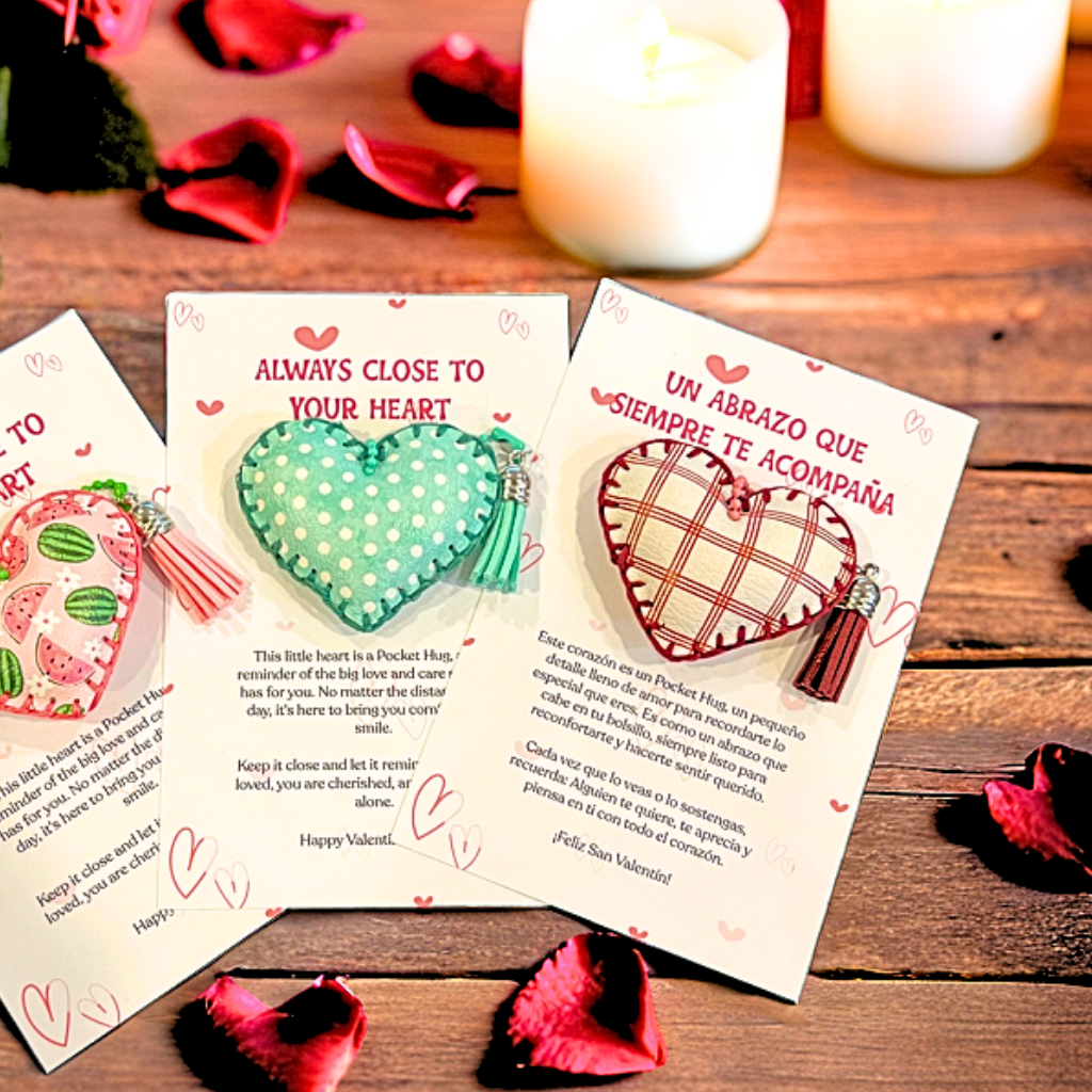 Three pocket hug hearts on message cards, including "Always Close to Your Heart" and a Spanish card, on a wood table