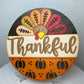 Decorative plate with a turkey design and 'Thankful' text on a stand.