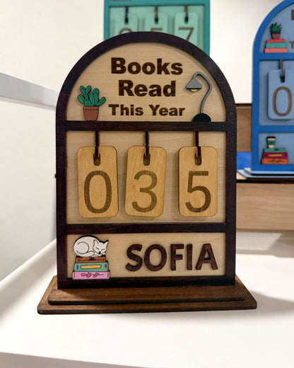 Souvenir Design Books Read This Year wooden counter in brown, number tiles showing 035 and the name SOFIA on the bottom shelf, with more color versions behind it
