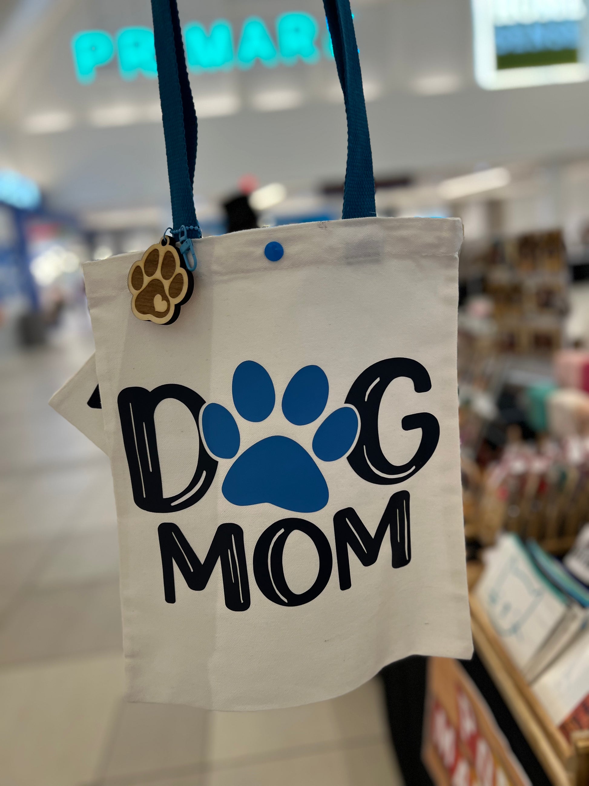Tote bag with 'Dog Mom' text and paw print in a store setting