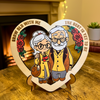 Heart-shaped wooden plaque with cartoon-style illustration of an elderly couple and romantic text.