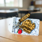Teacher keychain with the name "Miss Alex" engraved on the pencil charm, on its card on a classroom desk