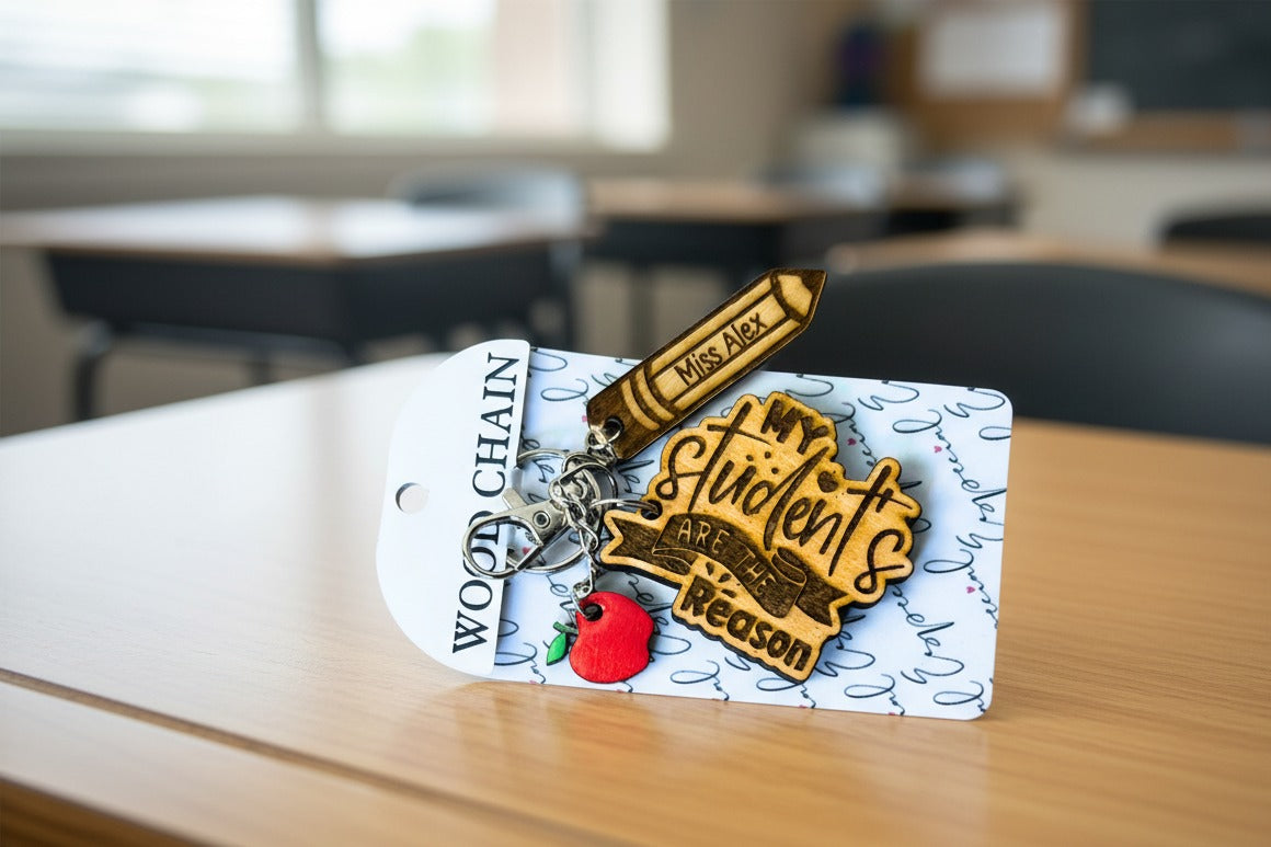 Teacher keychain with the name "Miss Alex" engraved on the pencil charm, on its card on a classroom desk